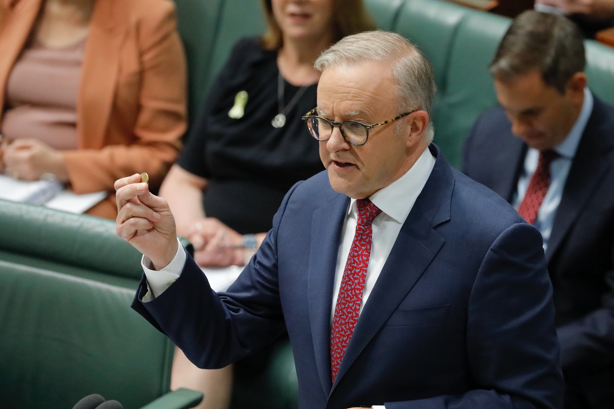 anthony albanese speaks in parliament holding a gold coin